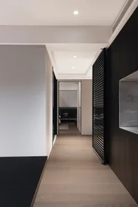A minimalist, wooden corridor interior with white walls and black accents.