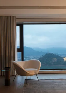 Modern living room featuring textured white furniture and a panoramic window overlooking mountains.
