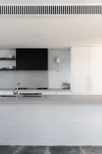 Modern kitchen with concrete countertops and white brick walls.
