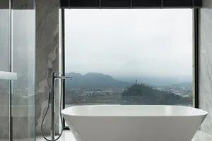 Modern residential bathroom featuring marble and ceramic finishes with a scenic view.