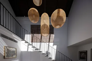 A staircase interior with four large, woven straw pendant lights hanging from the ceiling.