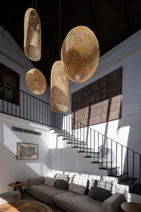 A modern living room with a comfortable couch, artistic wall decor, and large bamboo pendant lights hanging from a vaulted ce