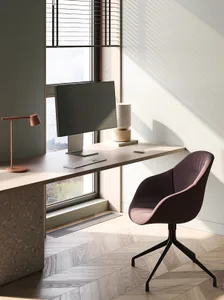 A minimalist home office featuring a wooden desk with a computer setup, a comfortable chair, and a sleek lamp.