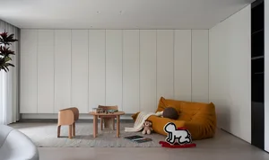 Minimalist living room with white walls, wooden furniture, leather couch, fabric toys, and modern design elements.