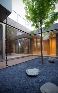 A minimalist residential courtyard with brick, glass, and wooden elements.