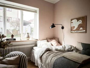 A minimalist bedroom with a bed, lamp, and artwork.
