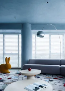 A modern living room with a grey sofa, decorative bunny chair, and a concrete floor.