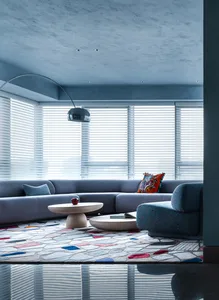 A modern living room featuring a terrazzo rug, contemporary furniture, and a floor lamp.