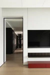 Modern living room with white walls, black furniture, and a red accent