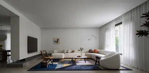 Interior view of a modern living room featuring a white sofa, coffee table, and chairs on a geometric rug.