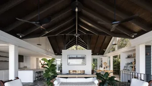 A modern living room featuring a tall ceiling, white sofa, and large windows.