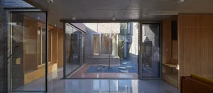 Modern residential interior featuring glass windows, brick walls, and concrete floors.