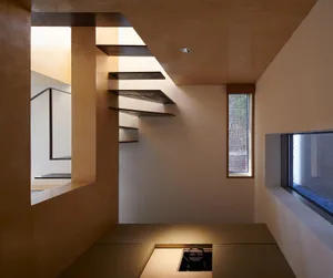 A modern residential interior featuring wooden and tiled flooring, geometric staircases, and natural light from windows.