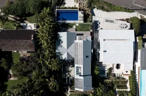 Aerial view of a modern residential home with a metal roof and outdoor patio area.