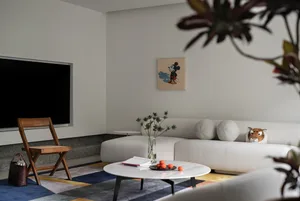 A modern Scandinavian-style living room with textured fabric furniture, a minimalist color palette, and decorative plants.