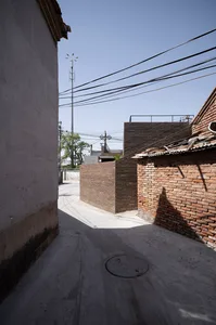 A narrow urban alley lined with brick buildings, featuring overhead power lines and a concrete pathway.