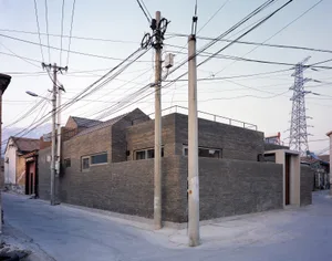 A modern, urban brick house with a rooftop terrace and several windows.