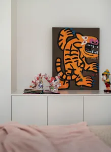 A canvas painting featuring a vibrant tiger illustration on a white shelving unit in a minimalist room setting.