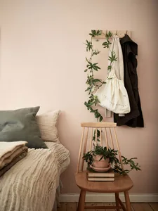 A minimalist bedroom featuring wooden furniture, cloth bedding, and a floral decoration.