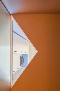 A minimalist interior features a glass window reflecting light and creating a geometric shape.