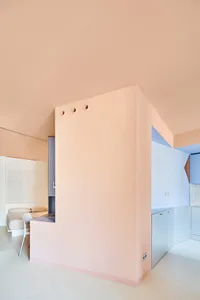 A modern minimalist residential interior with a pink wall and minimal decor.