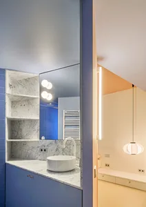 Modern bathroom with marble countertop, blue tile backsplash, and white shelving.