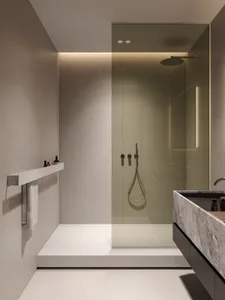 A modern minimalist bathroom featuring a glass shower stall, sleek sink, and contemporary fixtures.