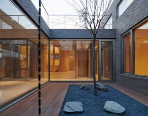 Modern residential courtyard featuring brick walls, glass walls, and stone rocks.