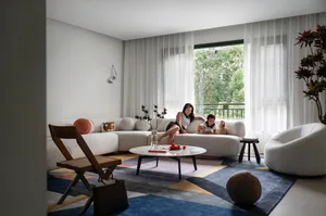 A modern living room with white sectional sofas, a round coffee table, and a colorful geometric rug.