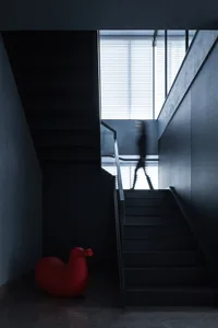 A minimalist architectural design featuring a black window and black stairs.