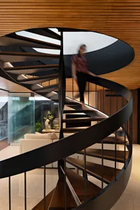 A modern residential interior featuring wooden floors, metal railings, and glass windows.