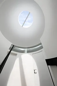 A modern white space with a glass ceiling allowing natural light to flood the area.