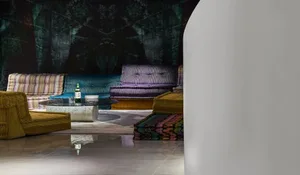 A modern lounge area with colorful upholstered furniture against a dark, abstract wall.