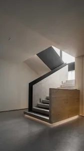 Modern industrial concrete stairs leading to a second floor with a skylight above.