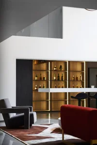 Lounge area featuring leather chairs, wooden shelves, and a bar counter.