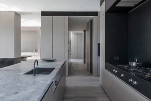 A minimalist kitchen featuring a concrete countertop and wooden cabinets.