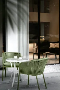 A modern, minimalist living room featuring green, woven furniture and a clean, uncluttered design.