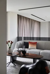A modern living room featuring a couch with textured fabric and a textured ceramic vase, placed on a textured rug, with a woo