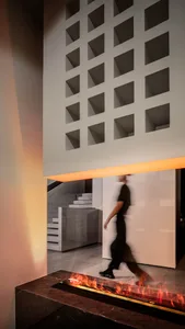 A modern interior living space featuring concrete walls and a fireplace with flames.