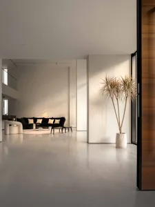 A modern, minimalist living room featuring a concrete floor, white walls, and a black and white color palette.