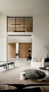 Minimalist living room with concrete flooring, white furniture, and a glass partition.