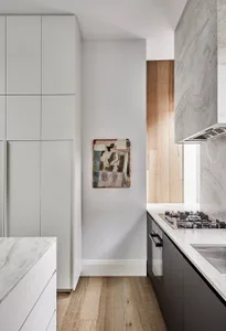 A modern minimalist kitchen with marble countertops and cabinets.