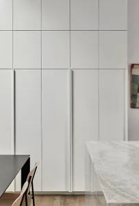 Minimalist kitchen featuring white marble countertops and cabinets.