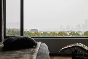 舒適的窗景空間，柔軟的毯子上擺著蓬鬆的枕頭，旁邊擺放現代貴妃椅，眺望寧靜的景觀