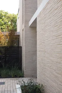 A minimalist building exterior with concrete walls and a black fence in front of tall trees.