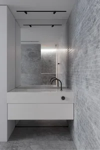 Modern minimalist bathroom with concrete walls and floor, featuring a floating vanity sink with black fixtures and a mirror.