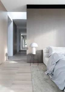 A modern bedroom featuring wooden paneling, a white lamp, and a comfortable-looking bed.