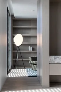 Modern interior space with light wood shelving, a floor lamp, and a marble desk.