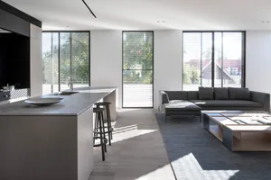 Modern living and dining room with concrete floor, minimalist motion blinds, wooden accents, and concrete countertops.