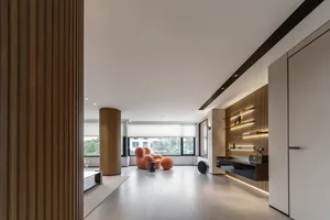 A modern living room featuring a concrete floor, wooden furniture, and minimalist decor.